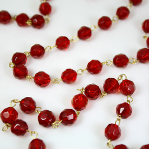 Catena 100 cm perle Ø 10 mm sfaccettate cristallo rosso, spillo a occhiello ottonato brillante.