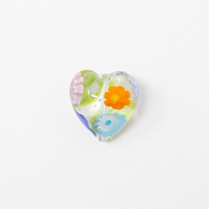 Perla cuore in vetro di Murano con Murrine millefiori, colore cristallo trasparente Ø14 mm. Con foro passante.